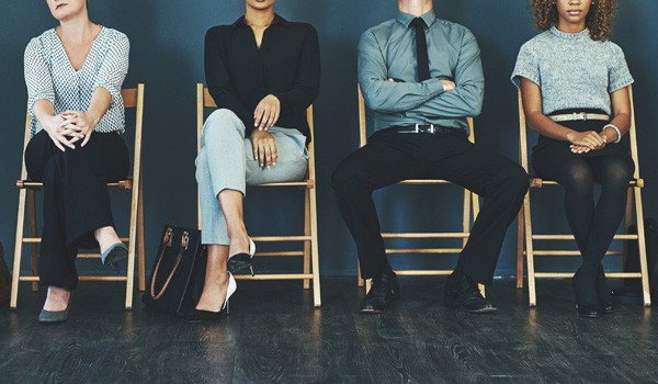 Four people sitting in chairs waiting