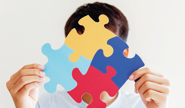 Person holding connected puzzle pieces in front of face