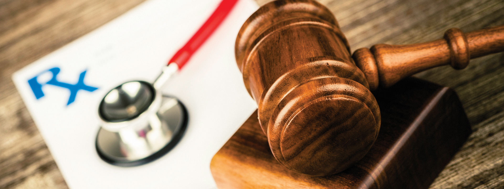 Closeup of a gavel, with a stethescope and prescription in background