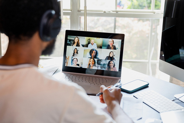 Over-the-shoulder view of man attending online meeting