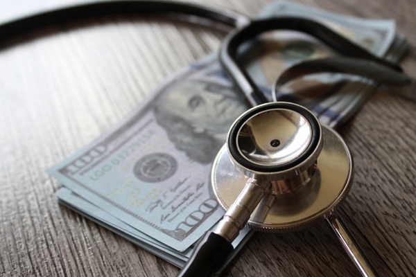 Stethoscope sits atop a stack of U.S. $100 bills.