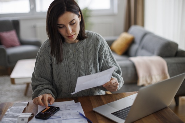 Woman looks at paperwork and pays bills at home
