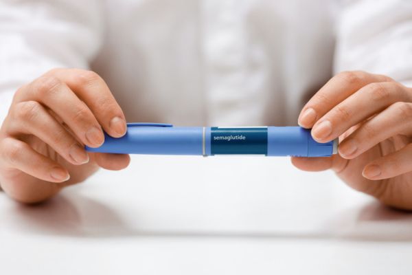Hands holding Semaglutide injection pen.